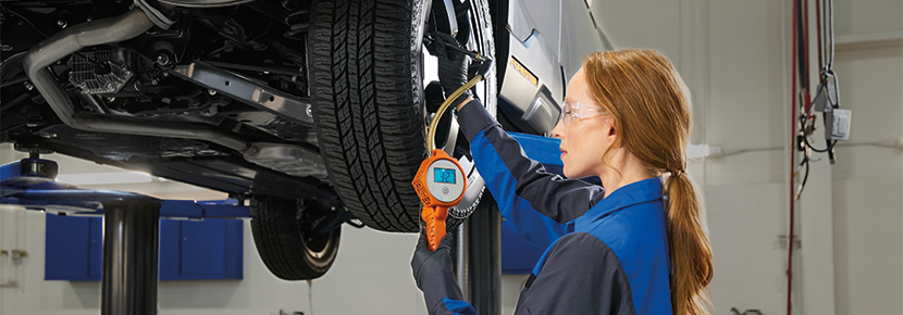 A Subaru technician checking tire pressure. | Flow Subaru of Charlottesville in Charlottesville VA