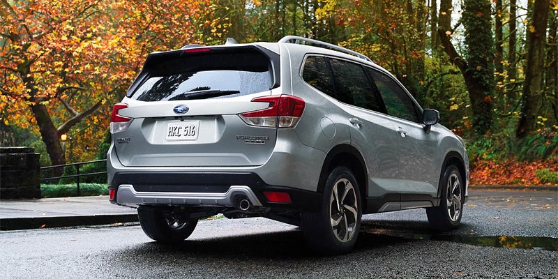Silver Subaru Forester viewed from the rear on a rain-dampened road with colorful fall foliage in the background
