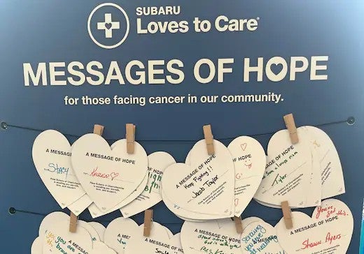 Blue sign: Subaru Loves to Care: Messages of Hope for those facing cancer Heart-shaped notes hang below