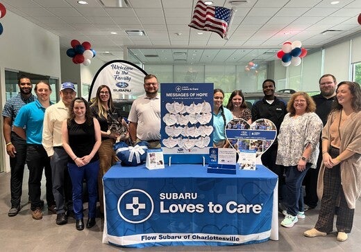 Group of people at a Subaru Loves to Care event with Messages of Hope display in a dealership