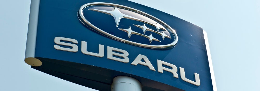 Subaru dealership sign featuring the Subaru logo and brand name on a blue background against a clear sky