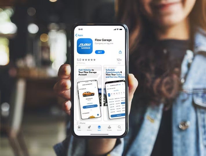 Person holding a smartphone displaying the Flow Garage app page on the App Store