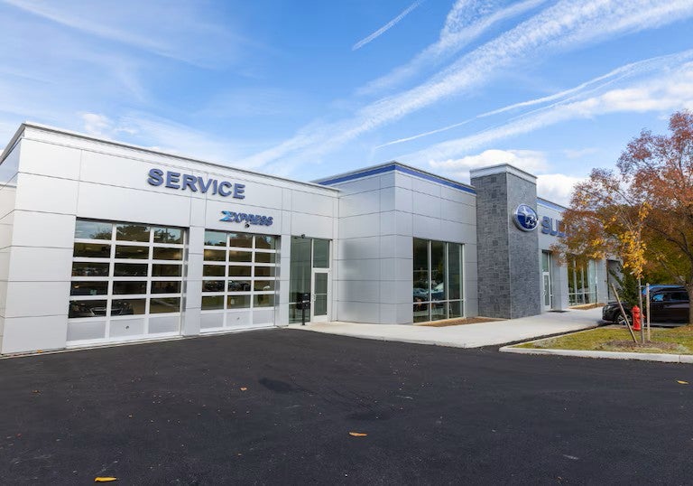 Modern car dealership and service center with service bay doors and large windows.