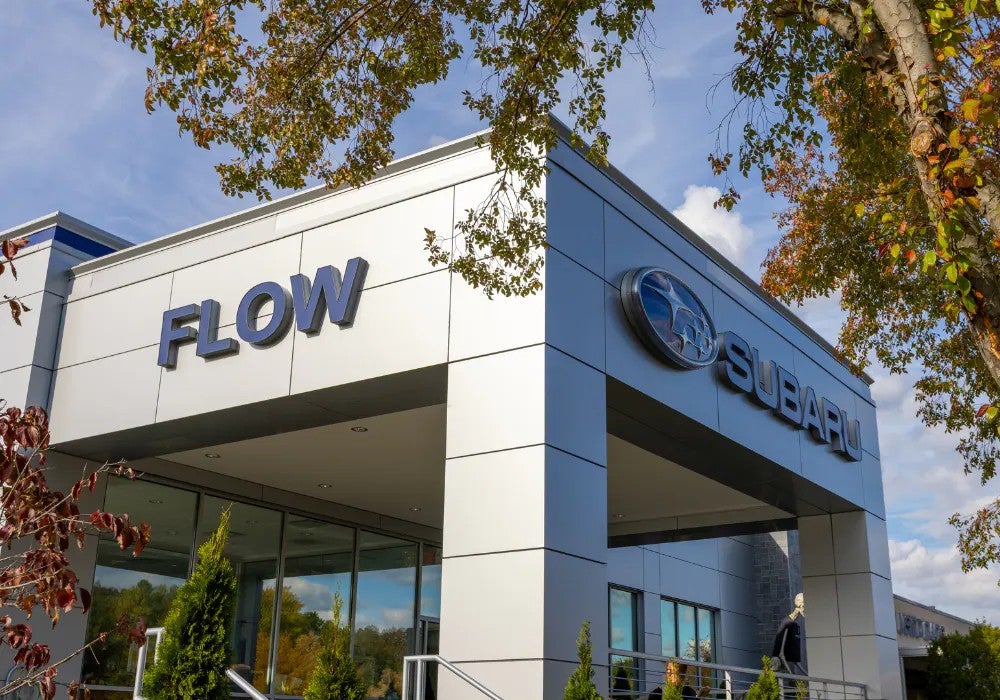 Exterior view of a Subaru dealership with 'FLOW' and Subaru signage on a modern building