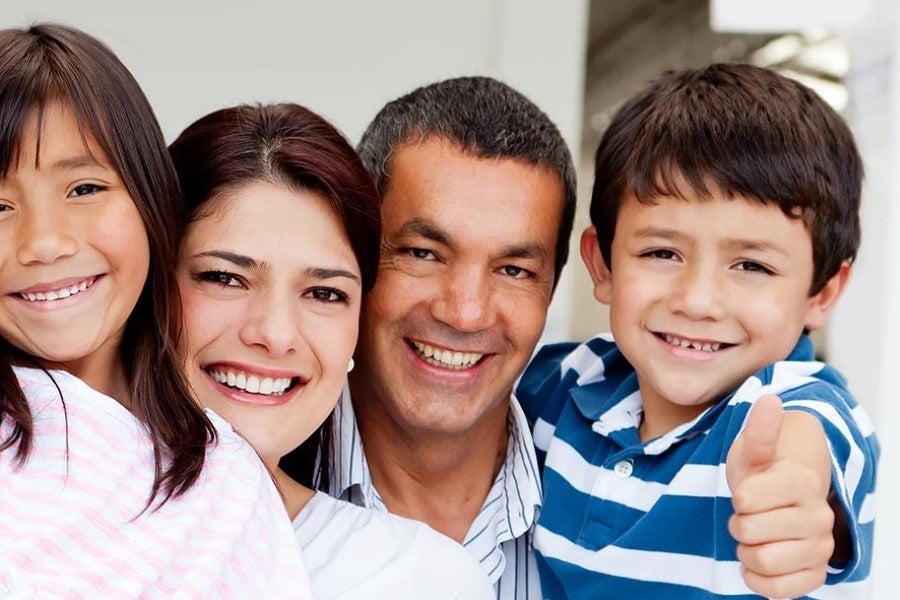 Group portrait of two adults and two children, with a child giving a thumbs-up